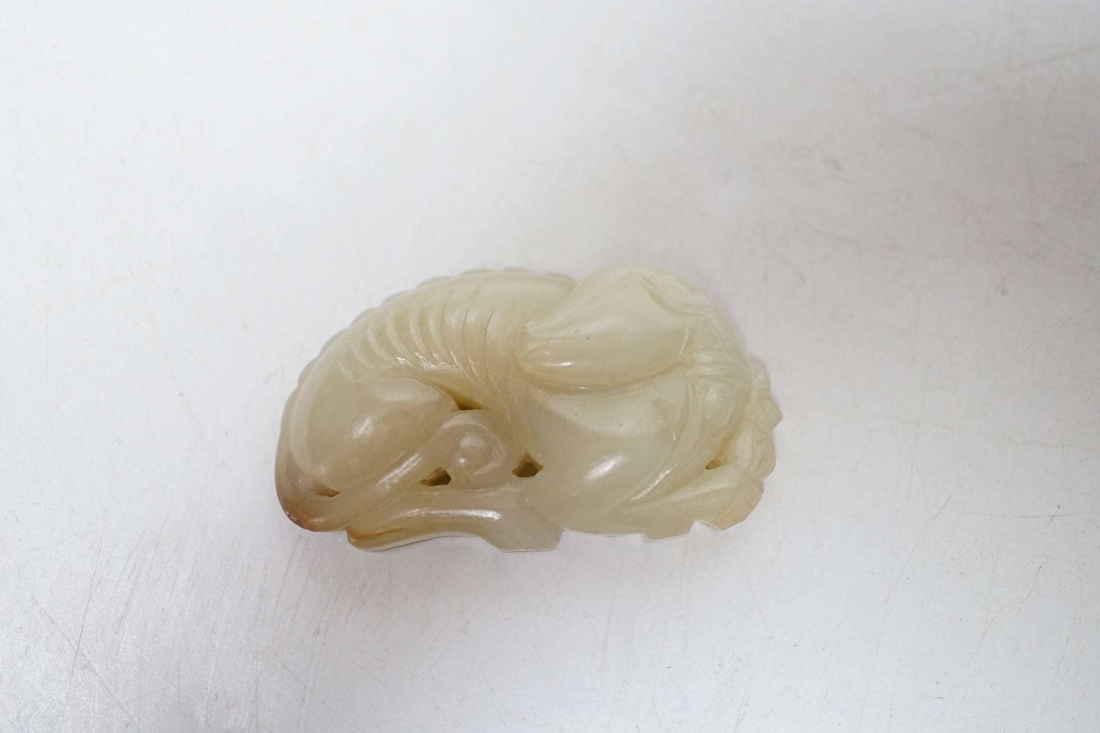 A Chinese pale celadon jade hound plaque, 5.2 cm